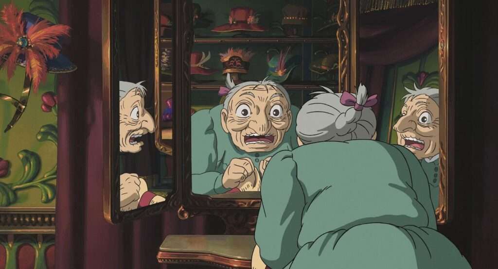 Sophie transformada em uma idosa de 90 anos se olhando no espelho assustada