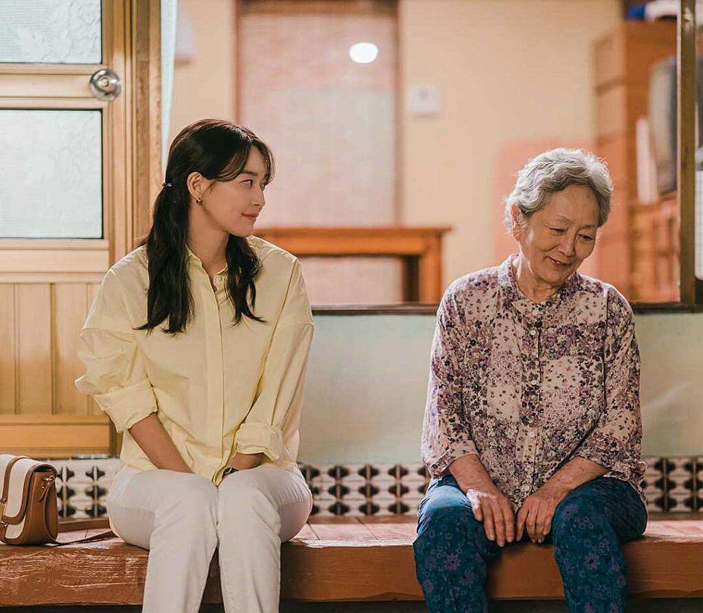 gam-ri, personagem mais velha de hometown cha cha cha, sentada na entrada de sua casa conversando com a protagonista